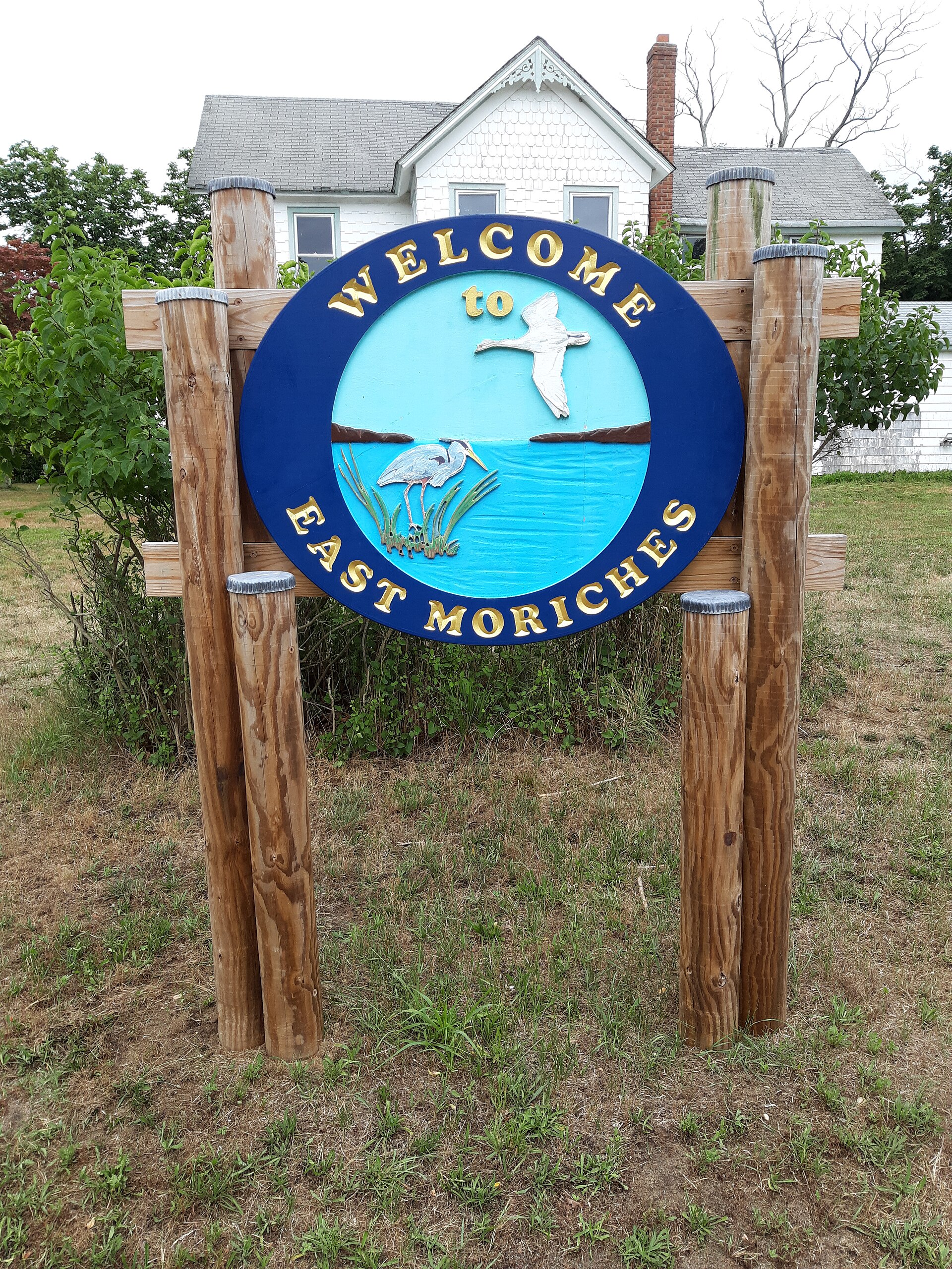 A carved wooden Welcome to East Moriches sign with a heron and swan