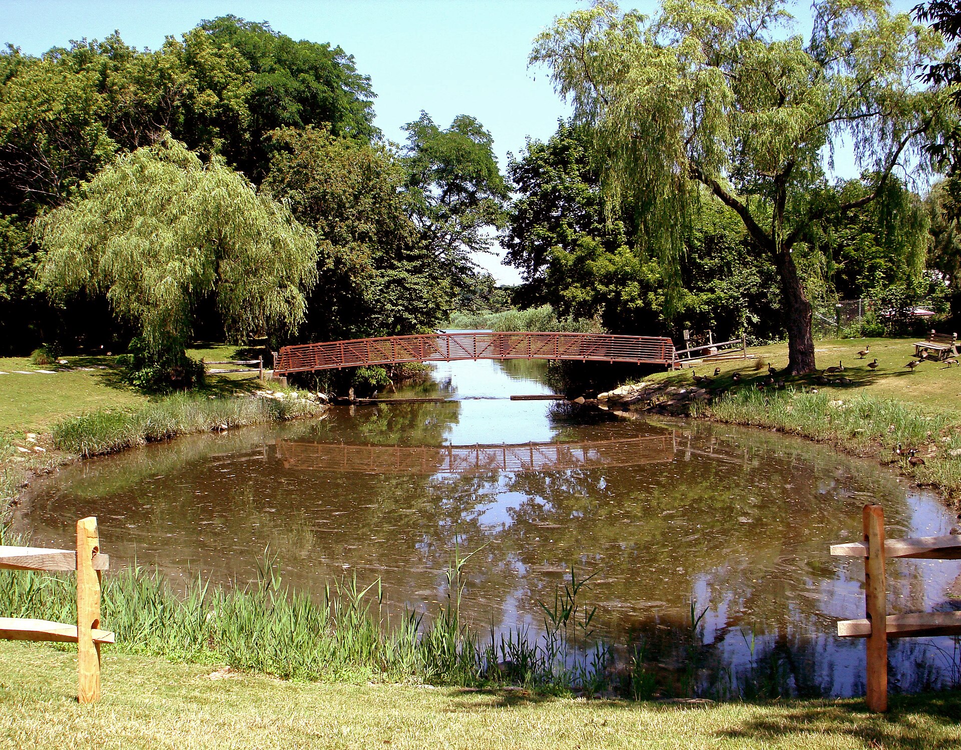 Red footbridge over a pond in a park in East Setauket
