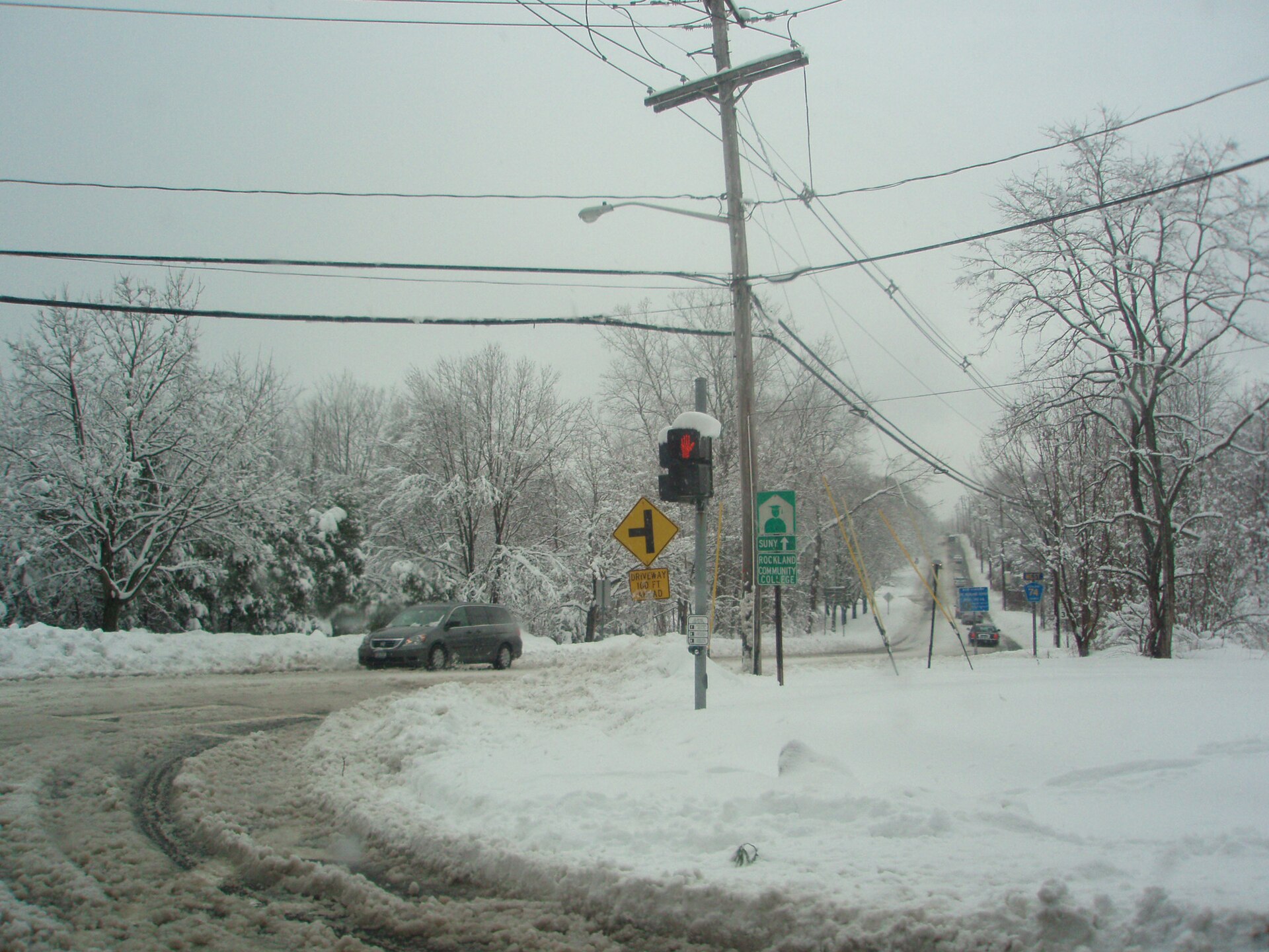 A snow-covered street corner in Viola, New York, with a traffic light and utility poles.