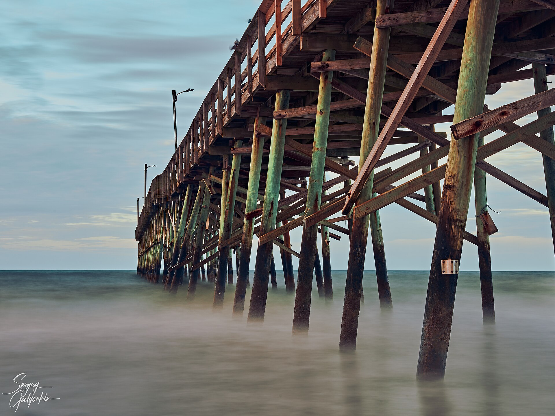 Wooden pilings of the Holden Beach pier over the ocean at dawn
