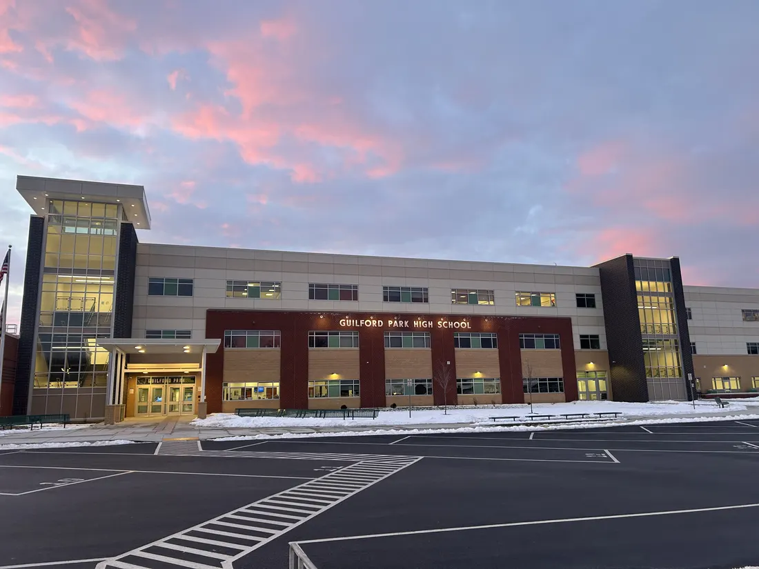 This is an image of Guilford Park High School in Jessup, MD. It shows the front of the building and is taken from the main parking lot, it is taken around sunset so the sky is pink and blue.
