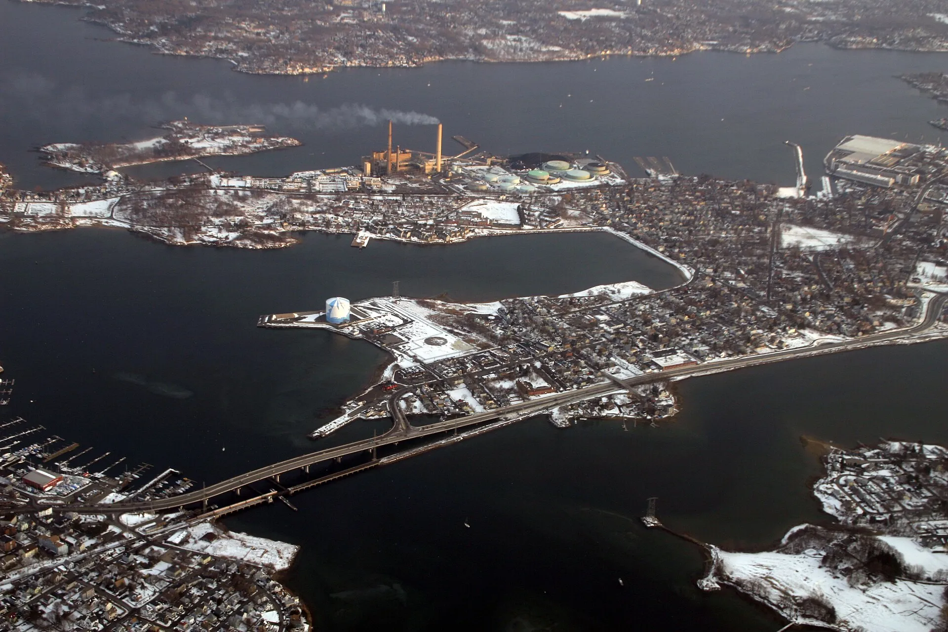 Bridge Street dominates this shot, most of which shows Salem, with the Salem Harbor Power Station on Salem Neck, off of which Winter Island protrudes. Marblehead is in the background. Beverly is on the left. The bridge crosses the Wooleston River.