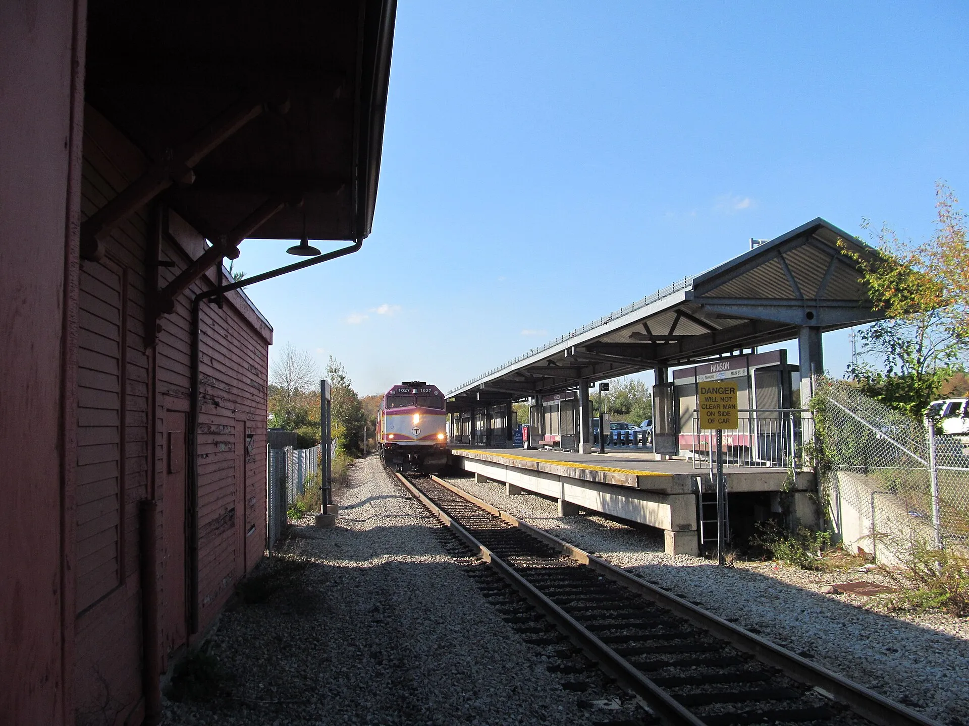 An MBTA Commuter Rail train at Hanson station, South Hanson, Massachusetts — the former South Hanson station building is at left.