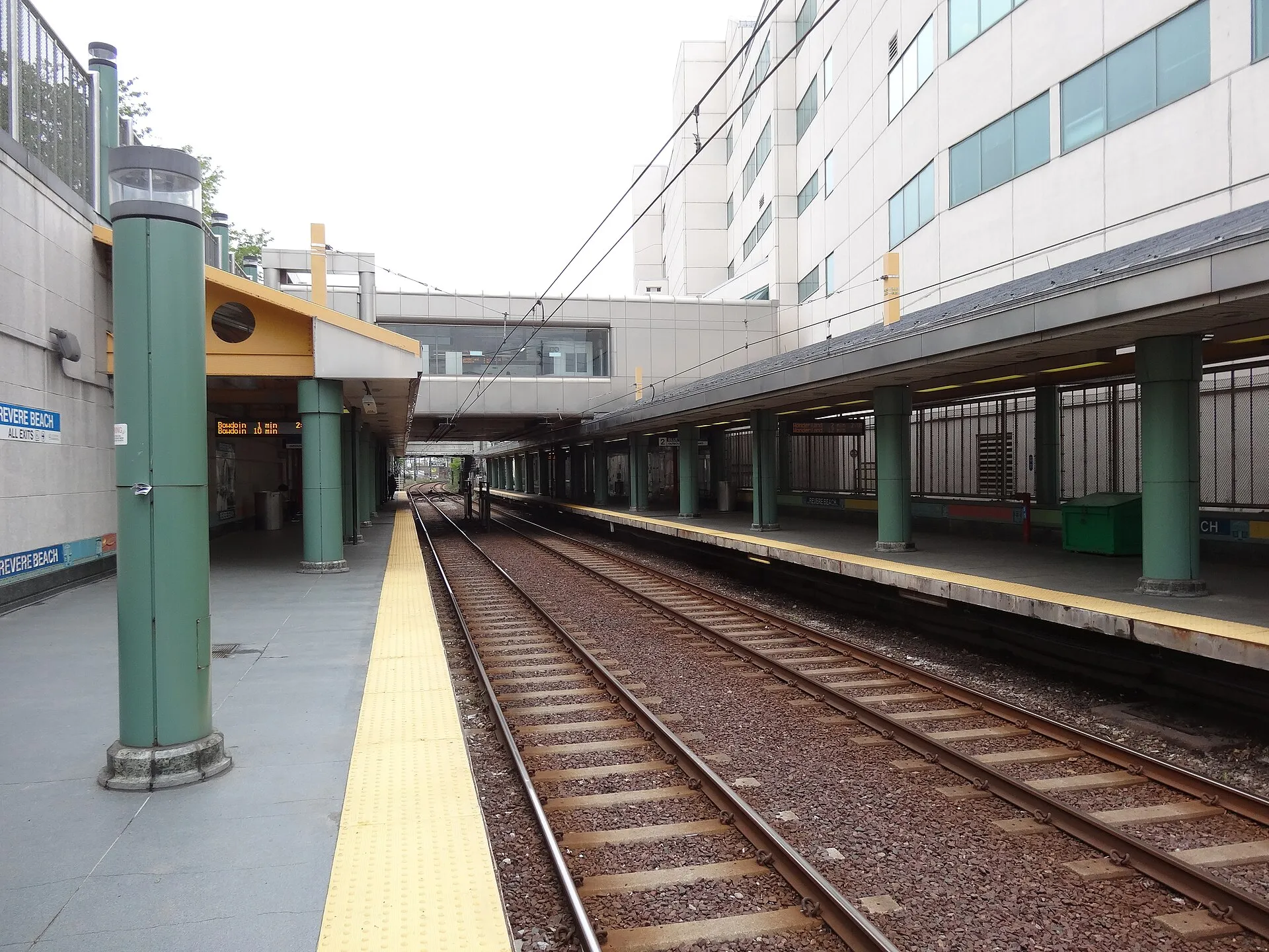 The inbound Blue Line platform at the Revere Beach station, looking outbound towards Wonderland, with a view of the pedestrian bridge connecting the two side platforms.