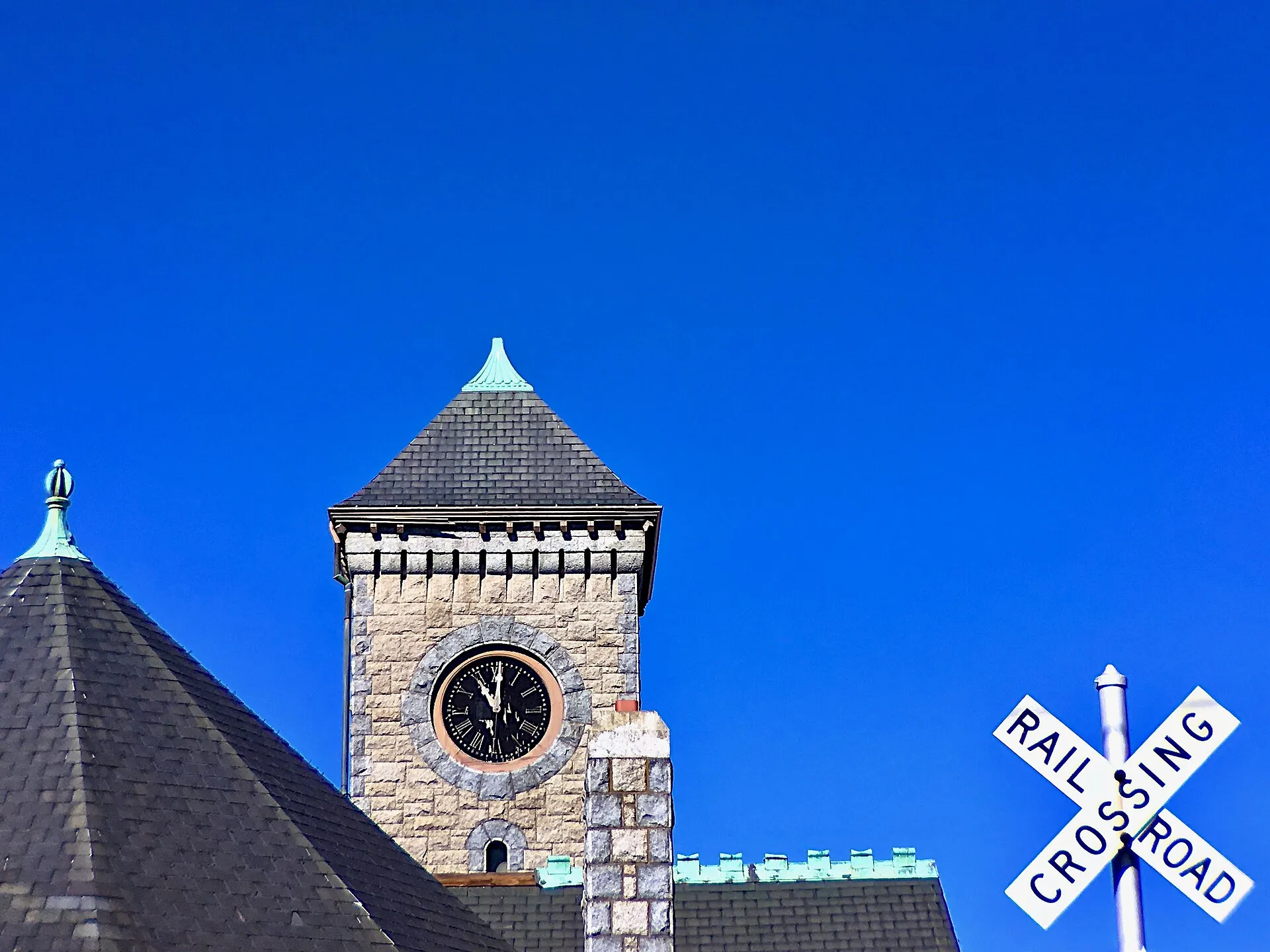 The clock tower at Stoughton Station, photographed against a clear blue sky, is located at 45 Wyman Street, Stoughton, Massachusetts.