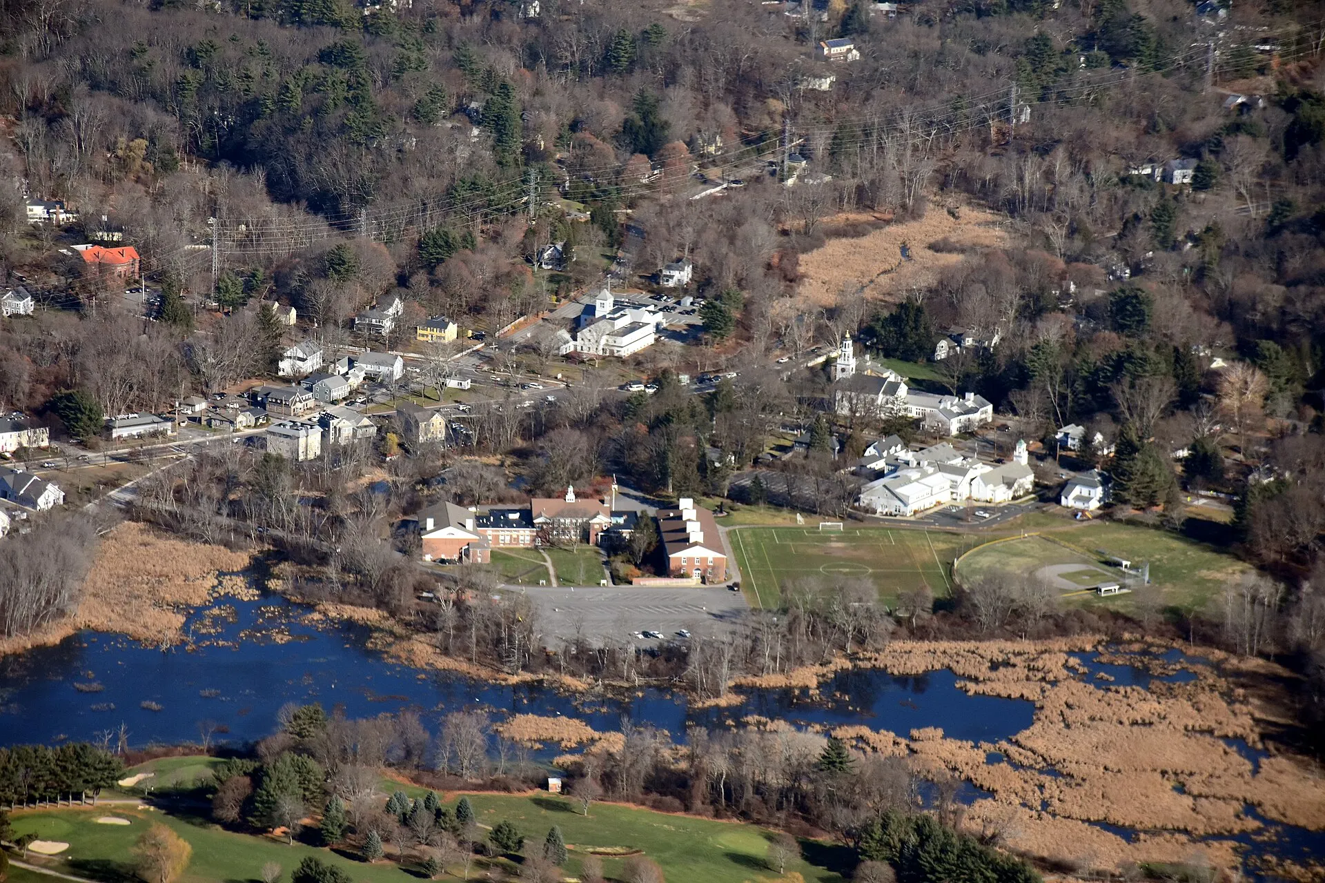 Aerial view of Wayland, Massachusetts town center, including Wayland Town Building, First Parish in Wayland, the Trinitarian Congregational Church, and Pine Brook in foreground.