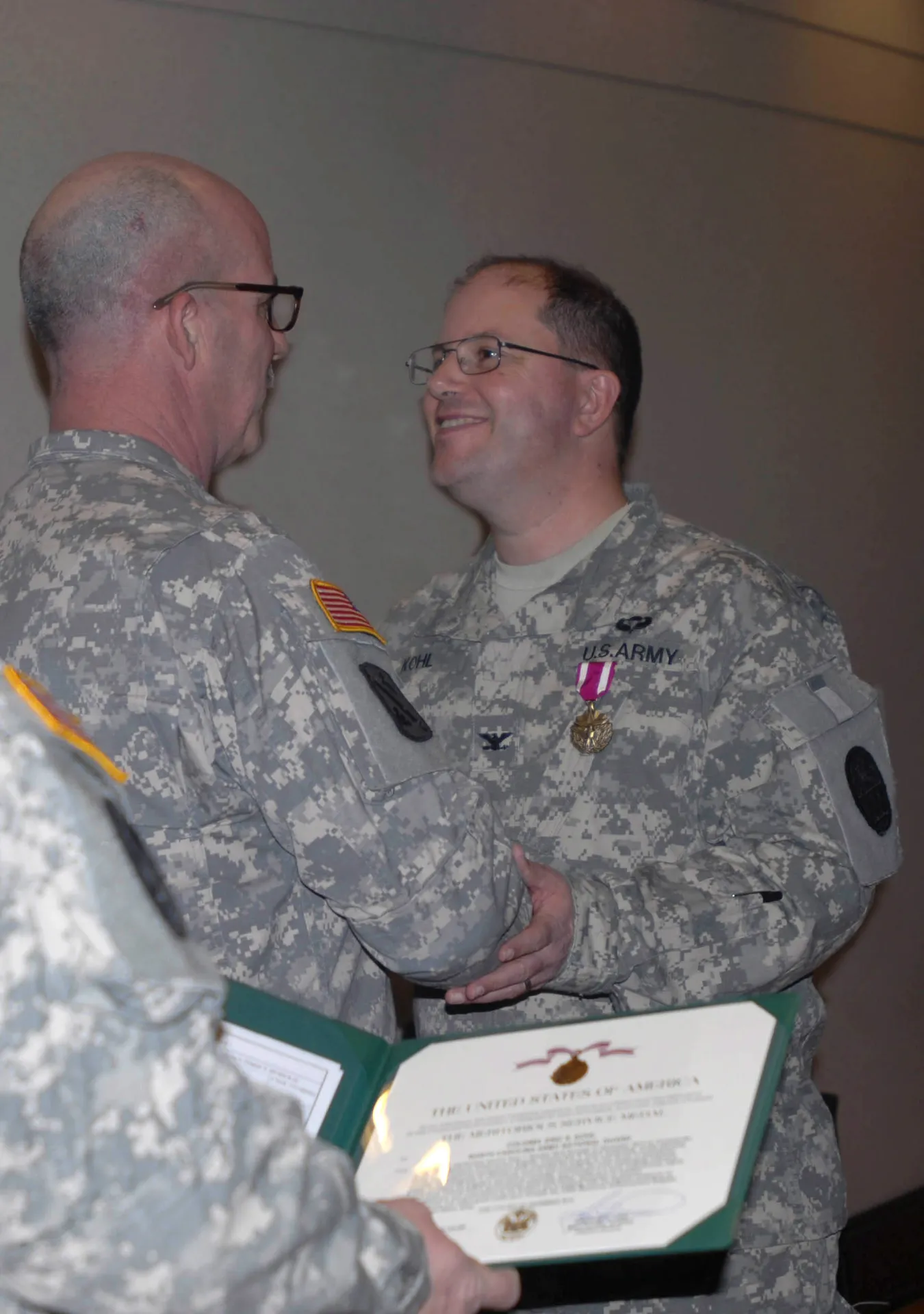 North Carolina Army National Guard Col. Eric Kohl (right), the outgoing commander of the 130th Maneuver Enhancement Brigade, receives an award from Brig. Gen. Kenneth Beard (left), the assistant...