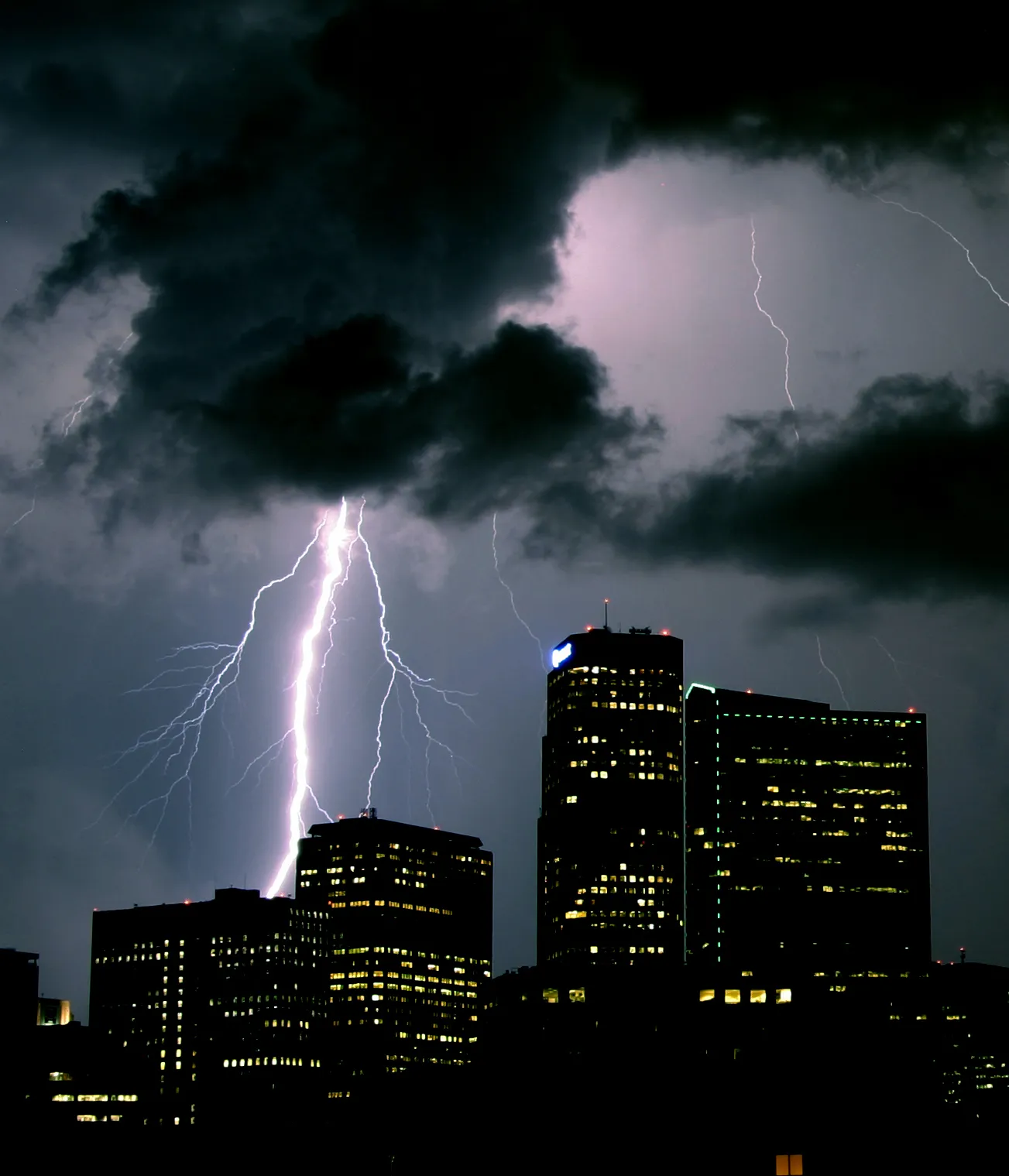 A large bolt strikes west of downtown Denver, with the west tower in plain view. Denver Lightning