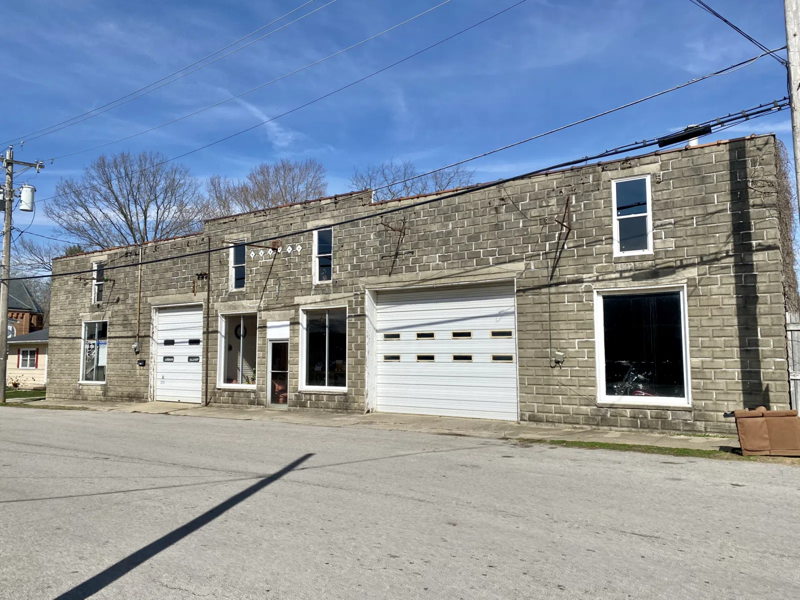Built in the early 20th Century, this concrete block building was constructed to serve as an automotive repair garage, and features a parapet with a terra cotta cap, concrete lintels, large garage openings, and one-over-