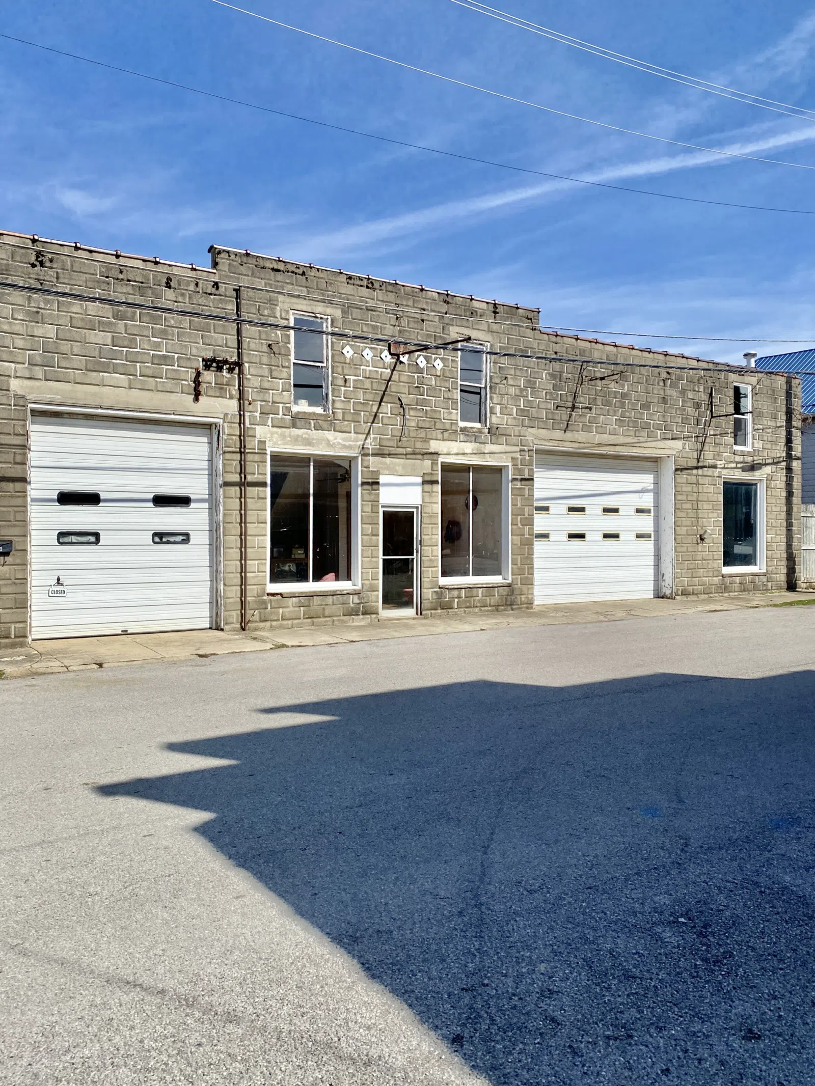 Built in the early 20th Century, this concrete block building was constructed to serve as an automotive repair garage, and features a parapet with a terra cotta cap, concrete lintels, large garage openings, and one-over-