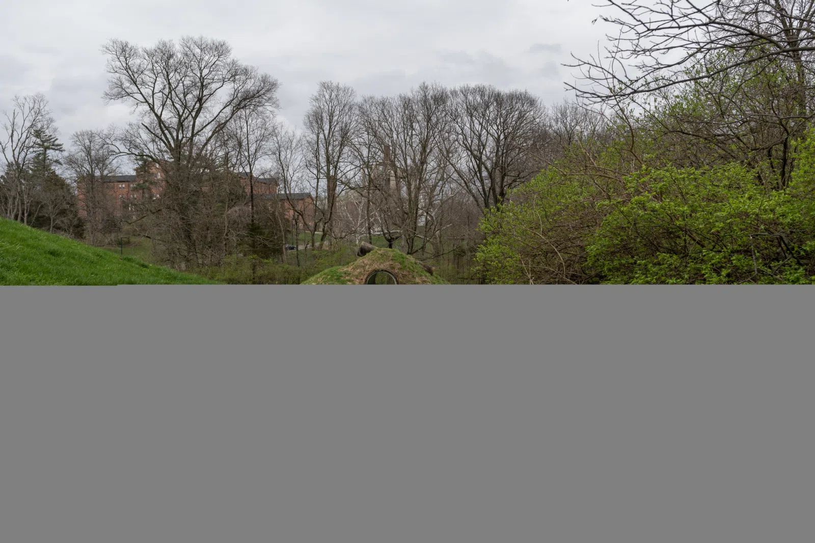 Approaching Nancy Holt's earthen sculpture, Star-Crossed, on the campus of Miami University's Art Museum in Oxford, Ohio on 13 April 2022. From this vantage the viewer can see through the walking tunnel. The observation