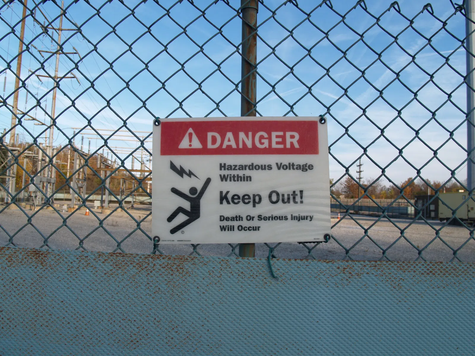 An ANSI Z535 'Danger - High voltage within' perimeter fence sign