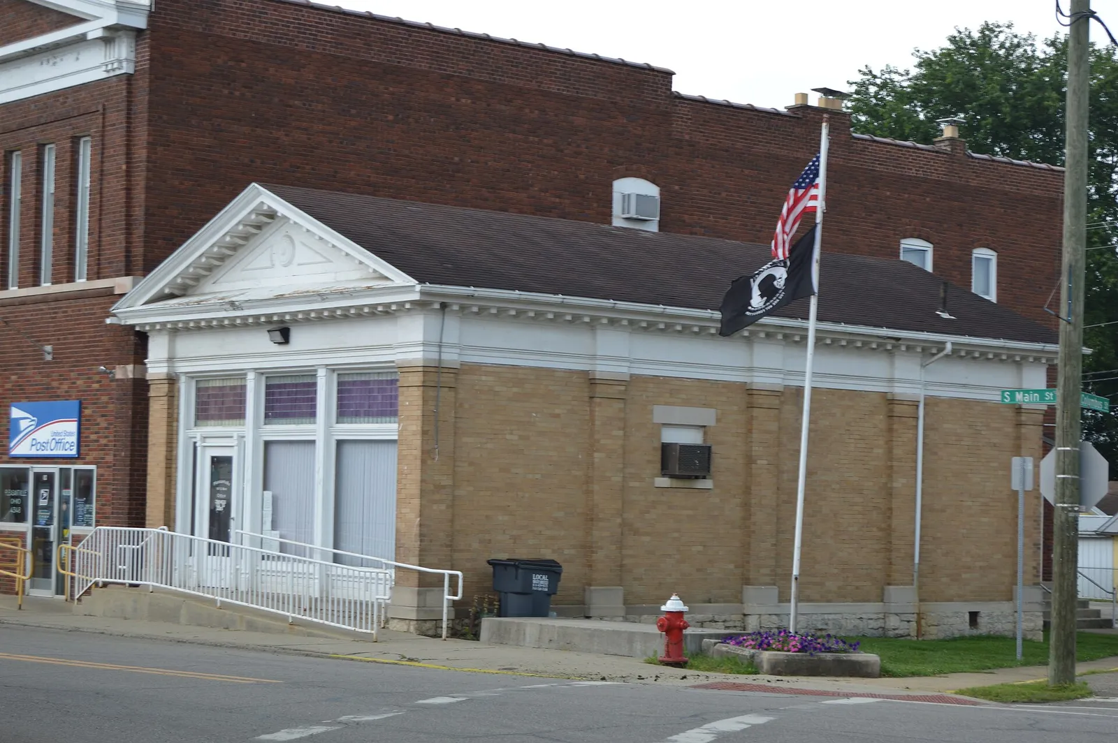 Front and northern side of a former bank, now a police station, located at 101 S. Main Street (State Route 188) in Pleasantville, Ohio, United States.