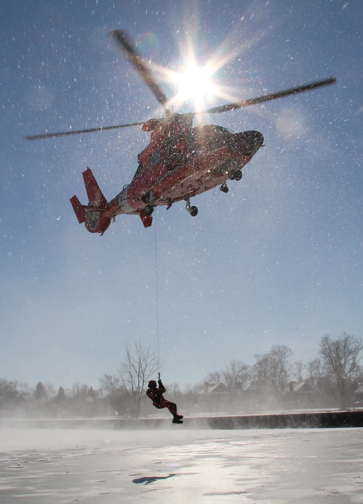 A rescue aircrew, aboard an MH-65C Dolphin helicopter from Coast Guard Air Station Detroit, conducts rescue training on ice-covered Lake St. Clair, Feb. 6, 2013.Training ensures crews remain ready to respond to maritime