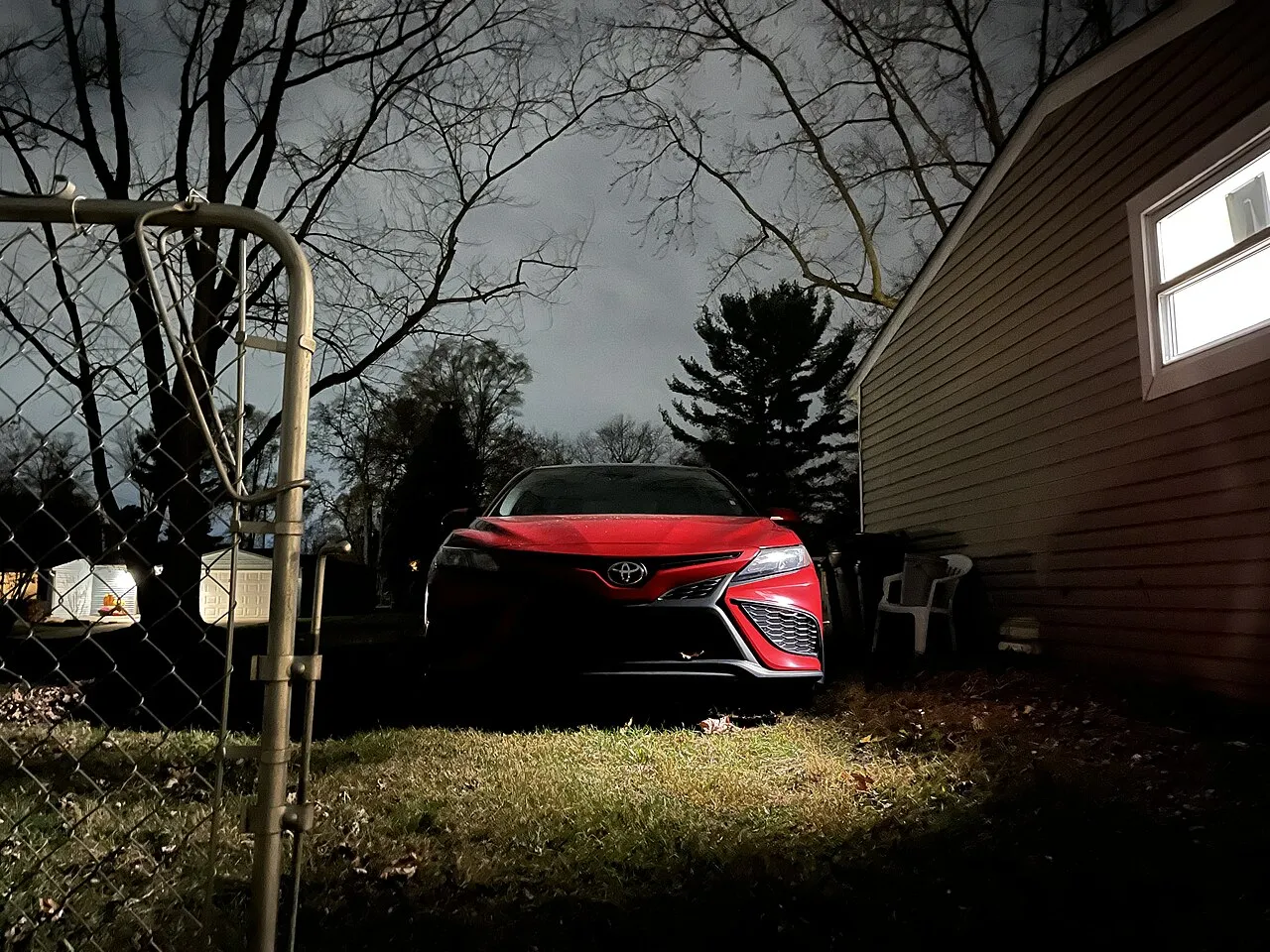 Red 2021 Toyota Camry parked in a driveway at night in the city of Walled Lake, Michigan, USA.