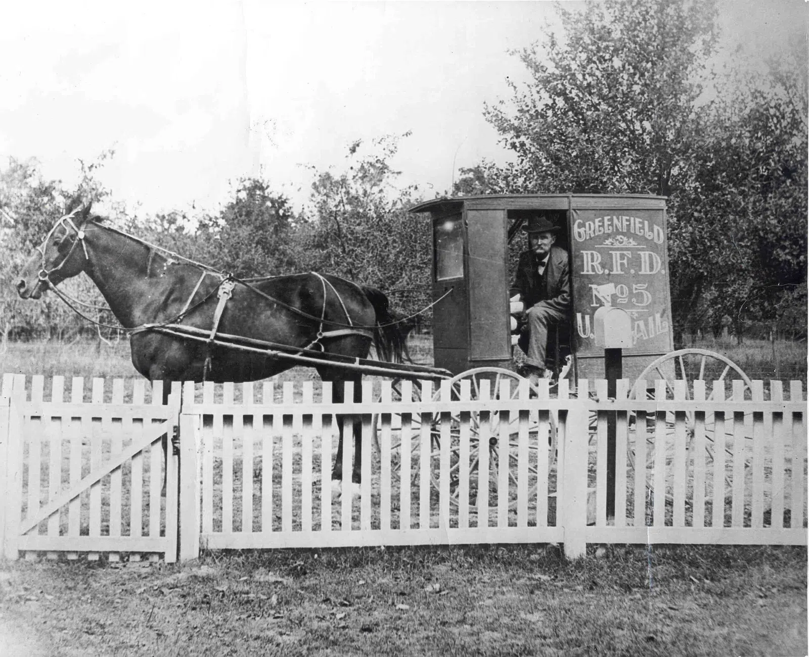 Nearby Greenfield landmark: Rural Free Delivery carrier in his wagon. The wagon is marked Greenfield / RFD / No. 5 / U.S. Mail. Route number five is…