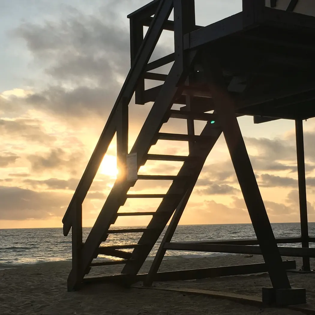 View of sunset through the steps of the life guard tower at Aliso Creek Beach in Laguna Niguel, CA..