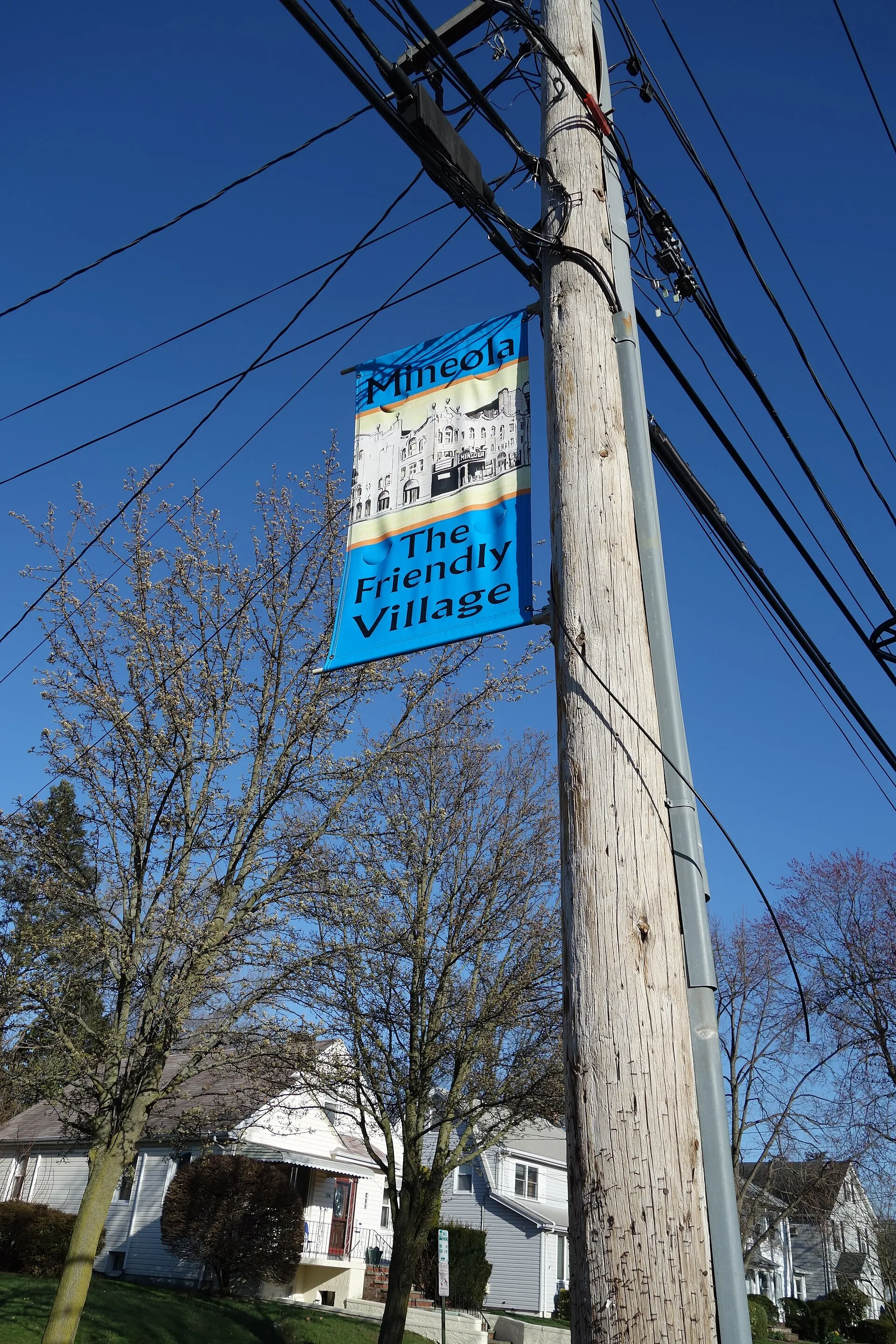 A banner in front of Mineola Memorial Library within Mineola Memorial Park: 'The Friendly Village'