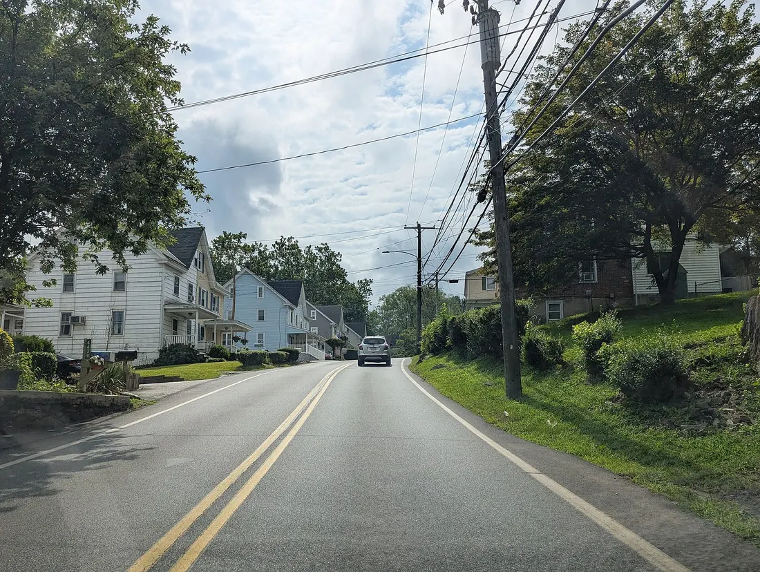Photo of eastbound Aston Mills Road in the village of Aston Mills within Aston Township, Pennsylvania. Photo taken looking southeast between Diamond Street and Hill Road.