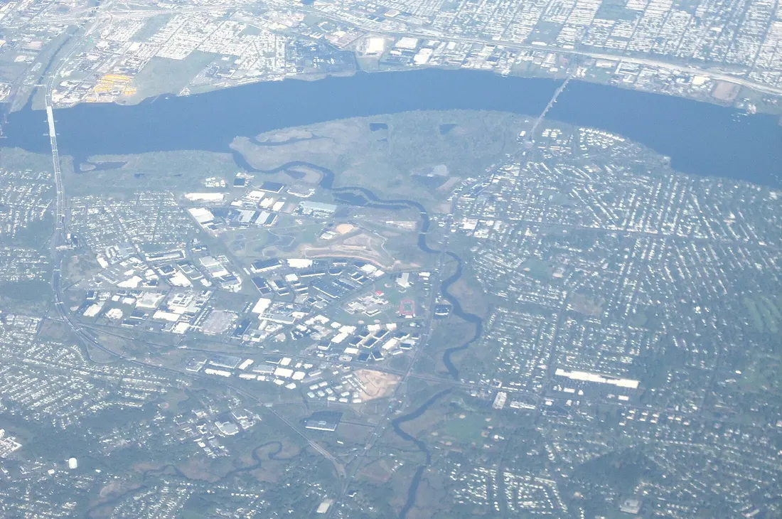 Oblique view of Pennsauken Creek (center) in New Jersey, flowing into the Delaware River, looking northwest. The large bridge in upper left is the Betsy Ross Bridge. The vegetated area to the right of the mouth of the