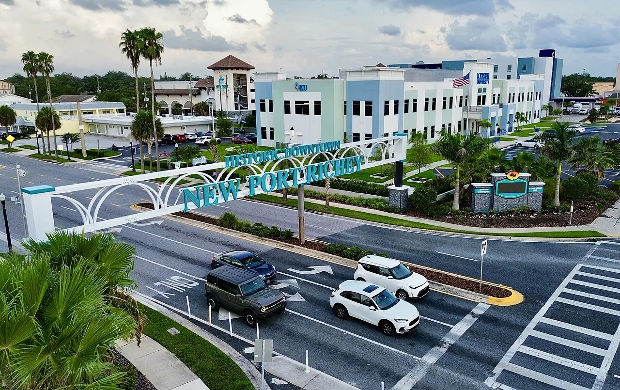 Drone shot capturing the Historic Downtown New Port Richey archway sign over Main Street, with the surrounding business district.