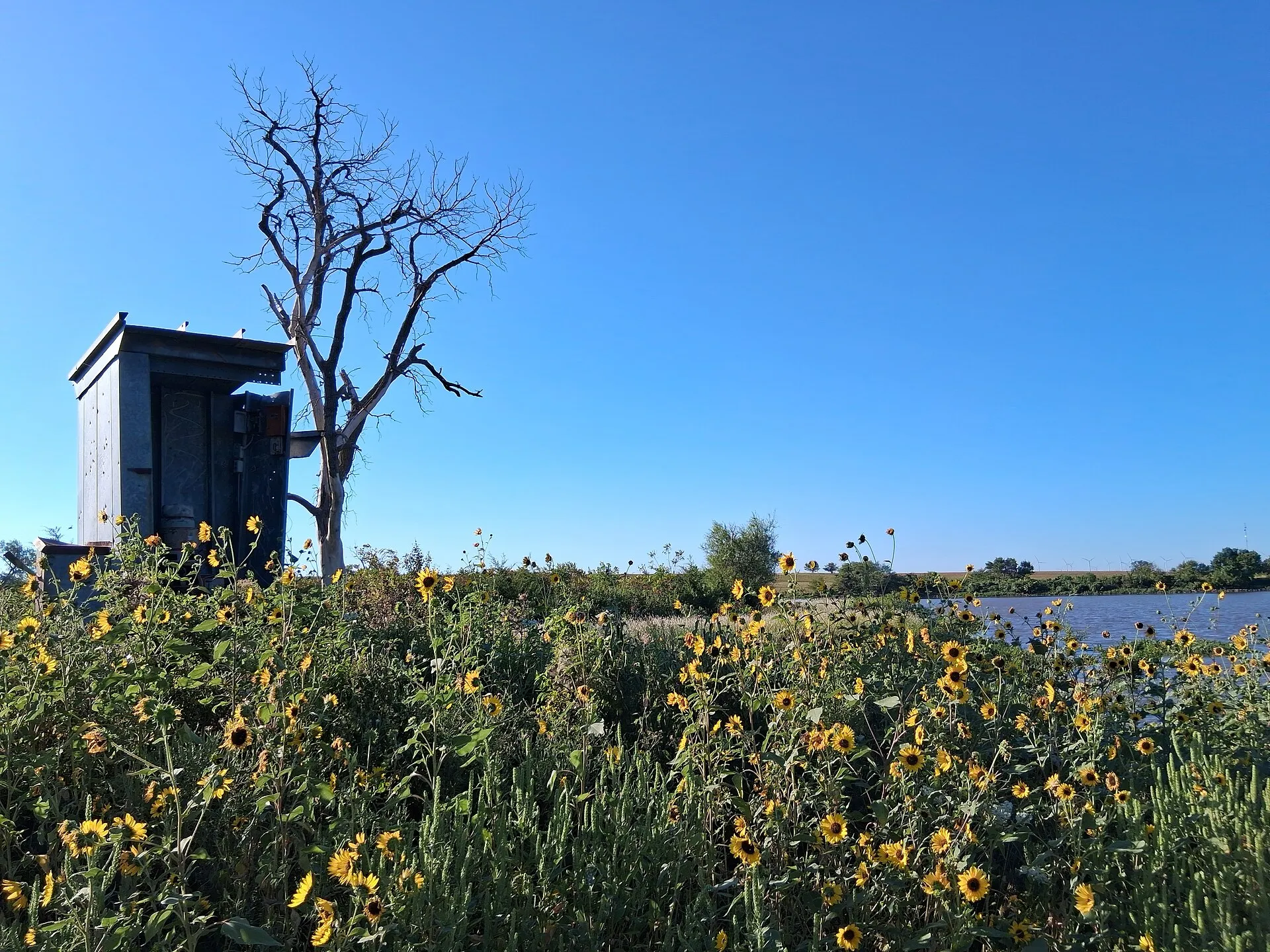 Old metal pumping station at the Beaumont St. Louis and San Francisco Railroad Retention Pond in Beaumont, Kansas. The Elk River Wind Project is faintly visible in the distance.